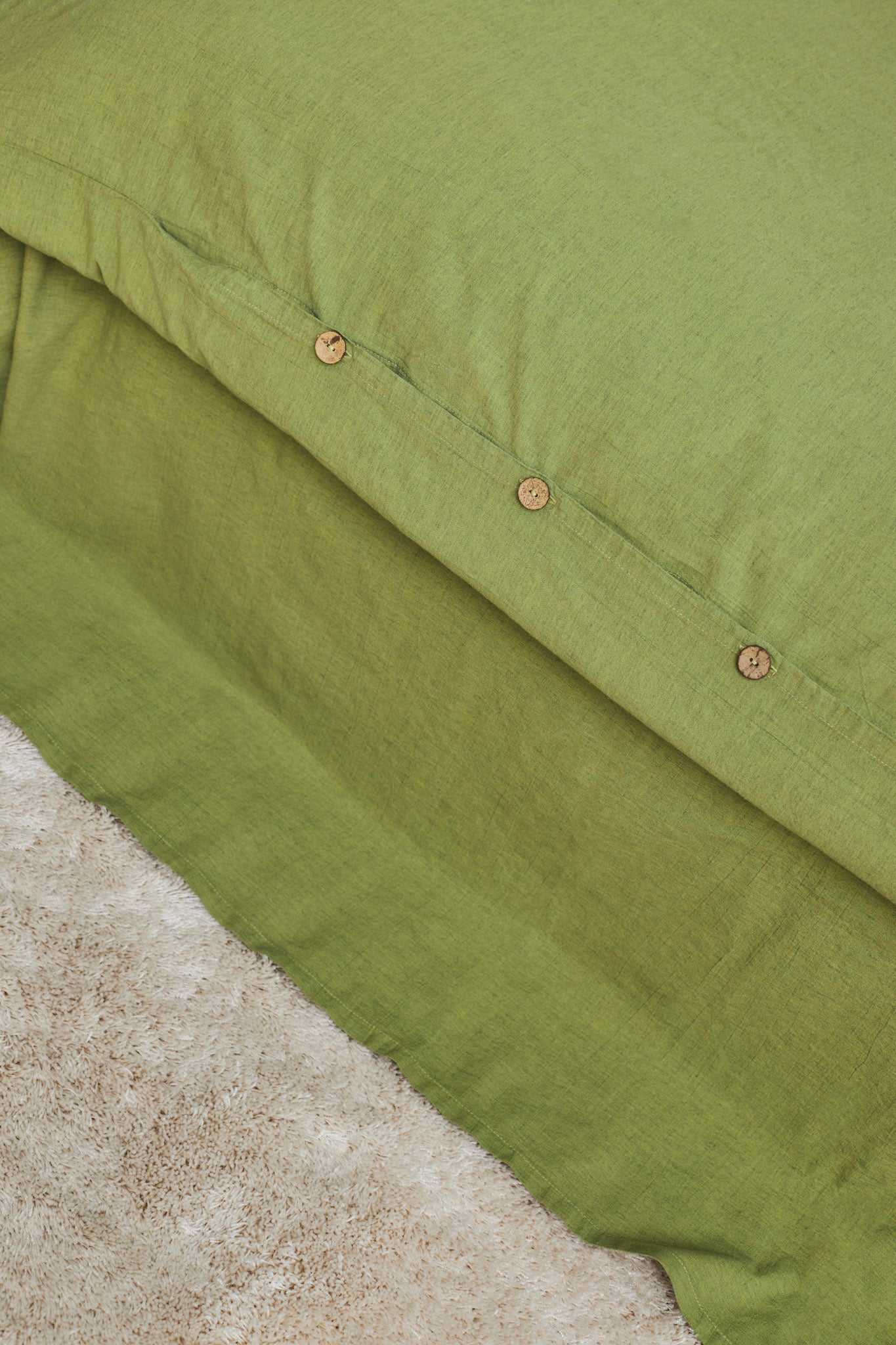 Close-up of a moss green linen duvet cover with buttons
