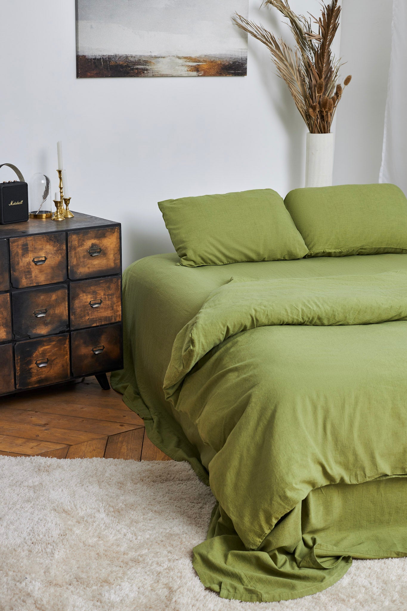 Linen duvet cover set in moss green on a bed in a room with wooden furniture and decor.