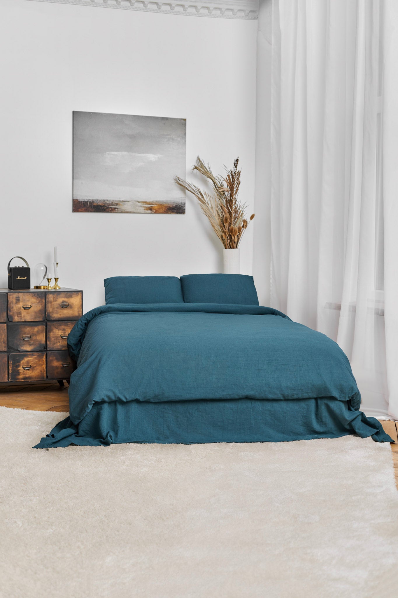 Stonewashed teal linen duvet cover set on a bed in a bedroom with a painting and decorative elements.