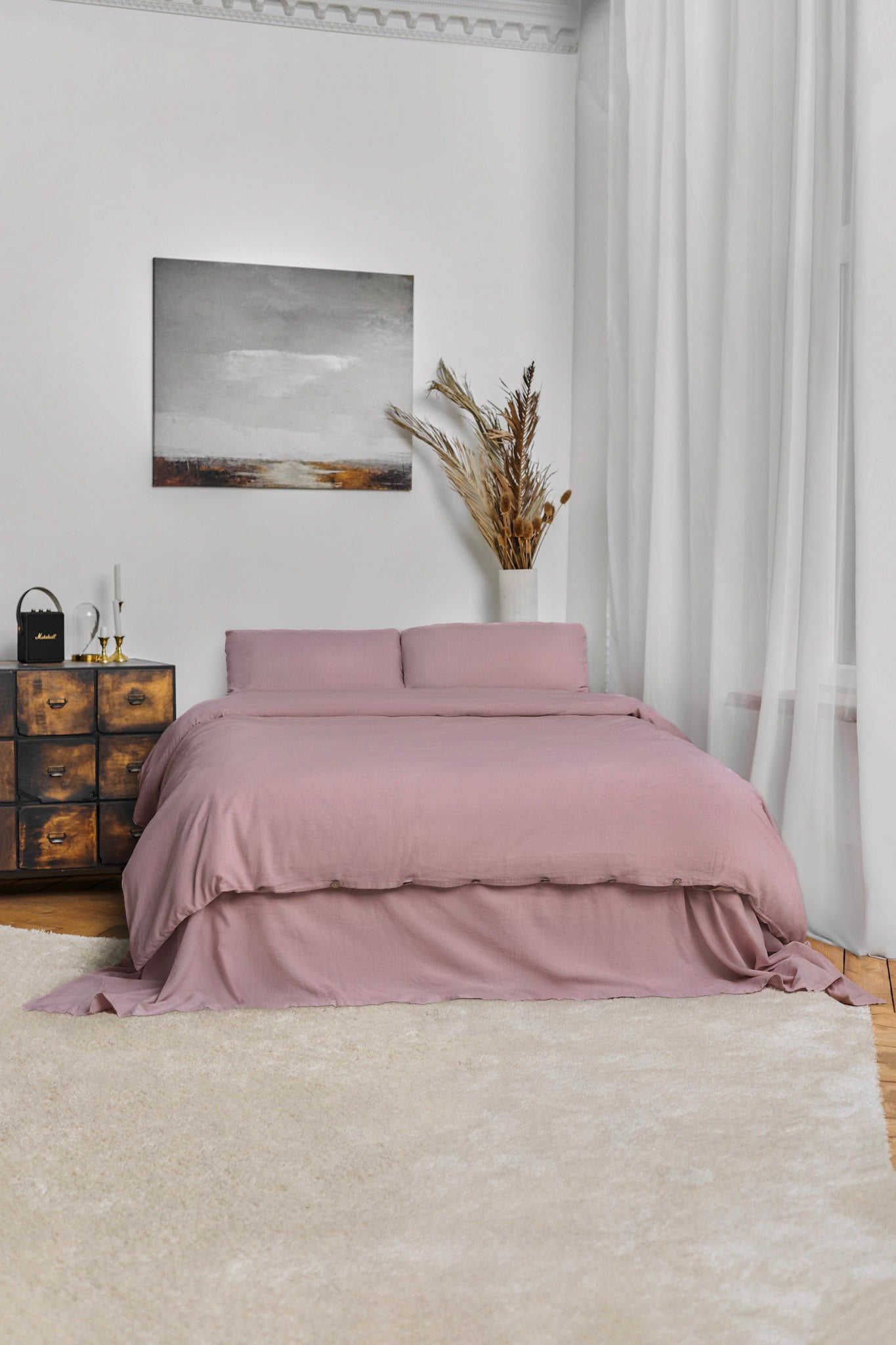 Bedroom with pink linen bedding - a set that includes a blush rose linen duvet cover and matching pillowcases in a bedroom setting with a painting and plant placed in a vase.