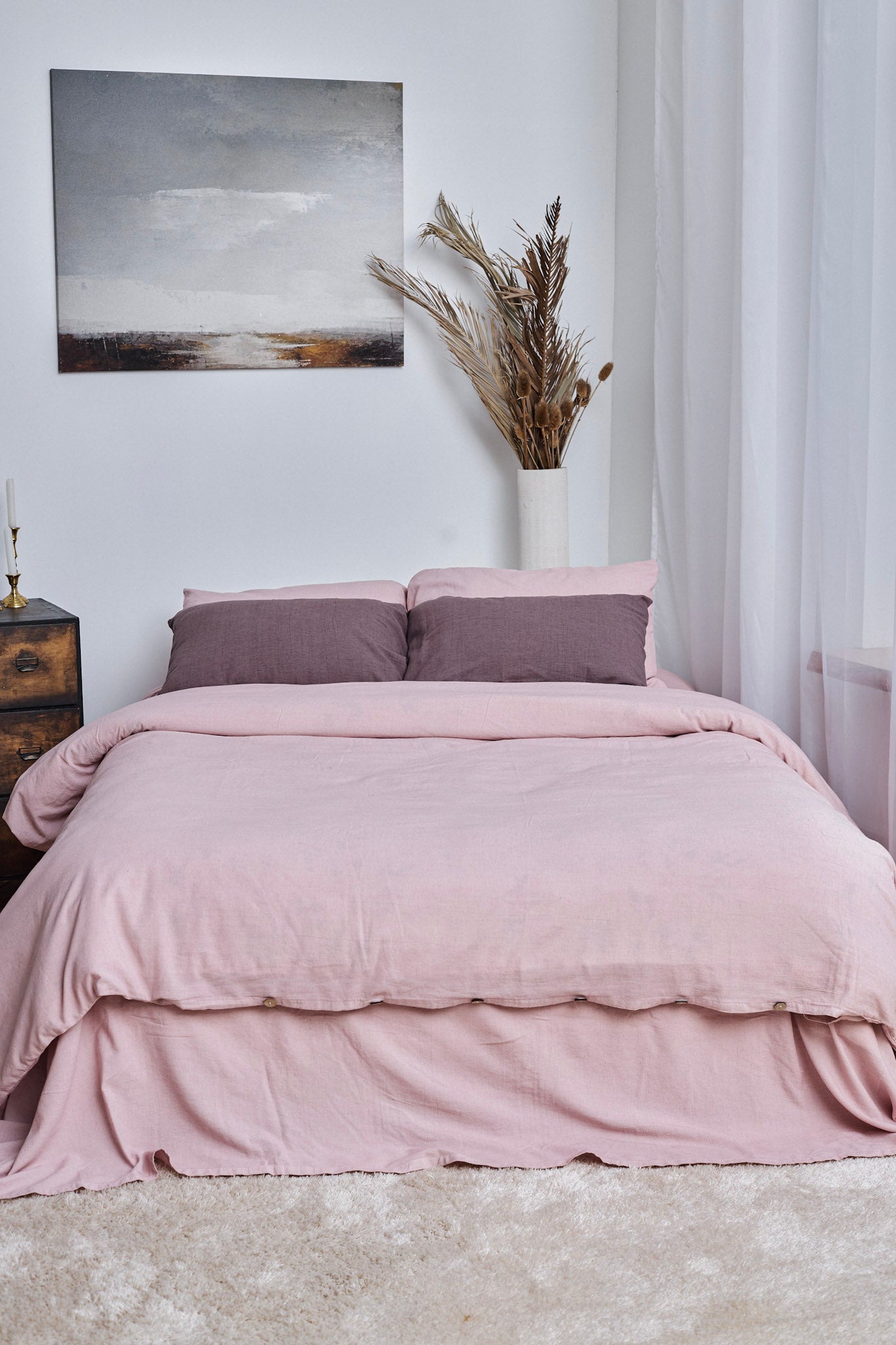 Pink linen duvet cover set on a bed in a bedroom with a painting and plant decor.