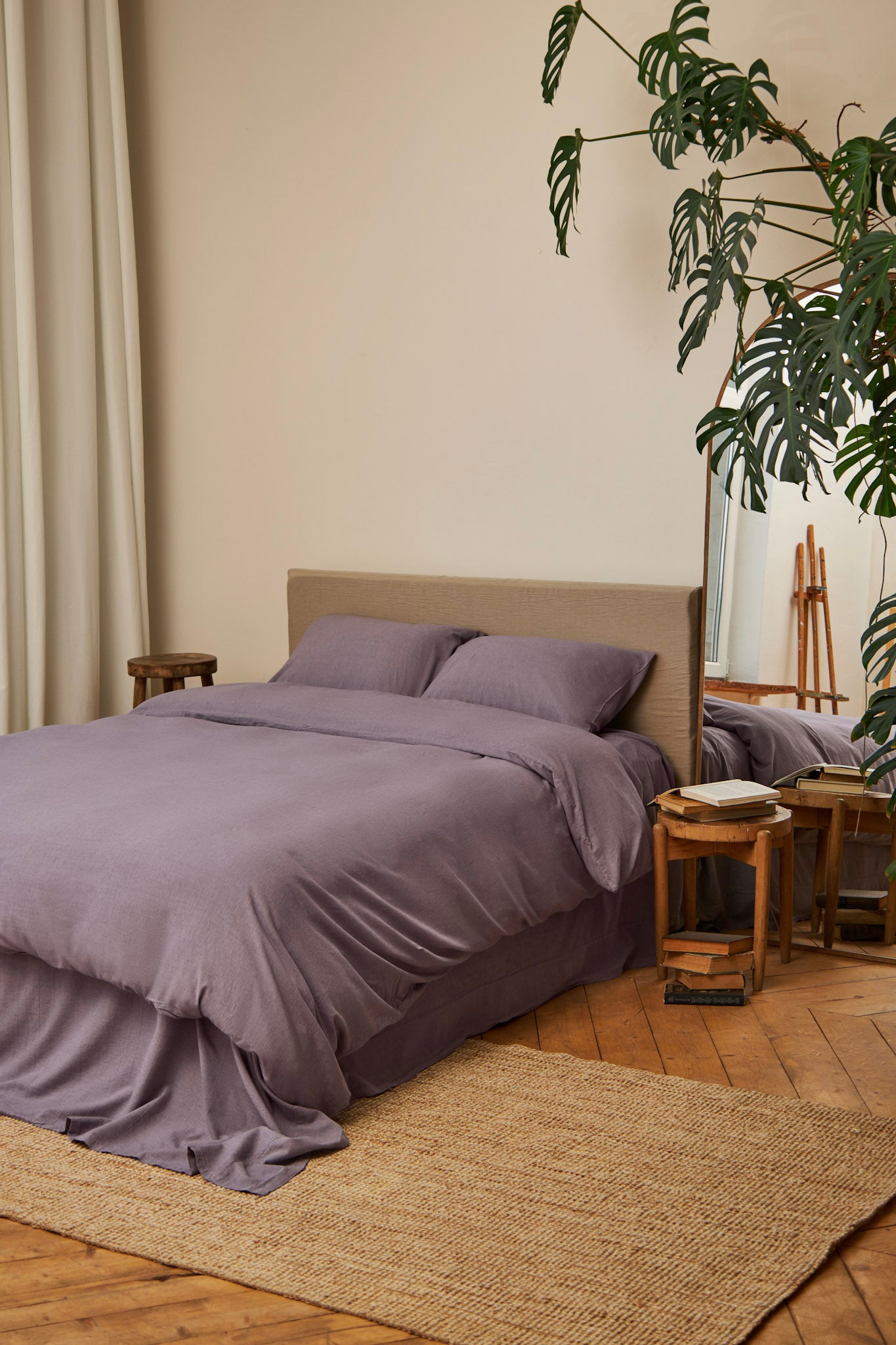 Bedroom with dusty purple linen bedding set, wooden floor, and plants
