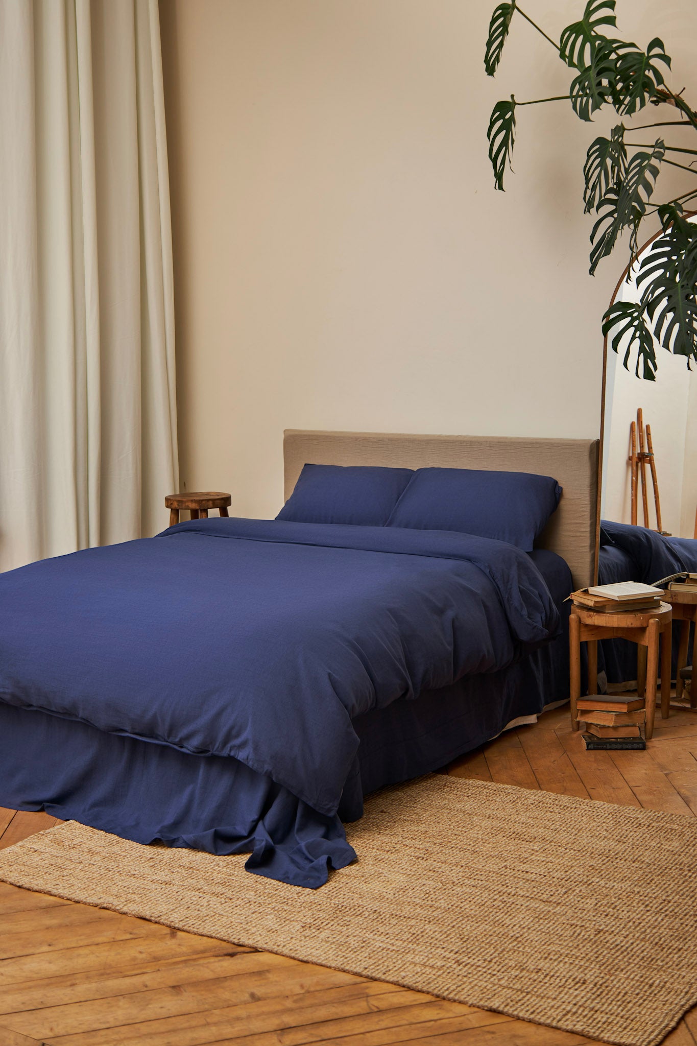 Navy blue duvet cover set on a bed in an elegant  bedroom with wooden flooring and a plant.